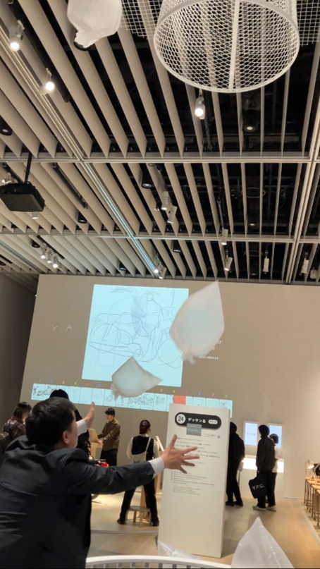 ステンレス光ではこの天井に吊るされたゴミ箱を製作しました。 この不思議な展示物、ご説明しますと 「デザインあ展neo」は「あるく」「たべる」「すわる」「もつ」など、わたしたちが行う行為(動詞)がテーマとなっています。 その数あるテーマの中で、「すてる」をテーマにしたブースにて、デザイナー様より依頼のあった写真のような展示会用の大型ゴミ箱（高さ1250mm、幅1000mm） を製作しました。 最初に「ゴミ箱を天井に吊るしたい」と御相談頂いたときはまったくイメージが湧きませんでした... この「すてる」のブースは実際に体験することが出来ます。 実際に「すてる」を体験してみました。